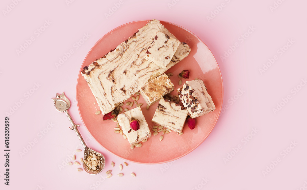 Plate with pieces of tasty marble halva on pink background