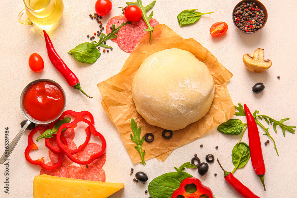 Raw dough and ingredients for preparing pizza on light background