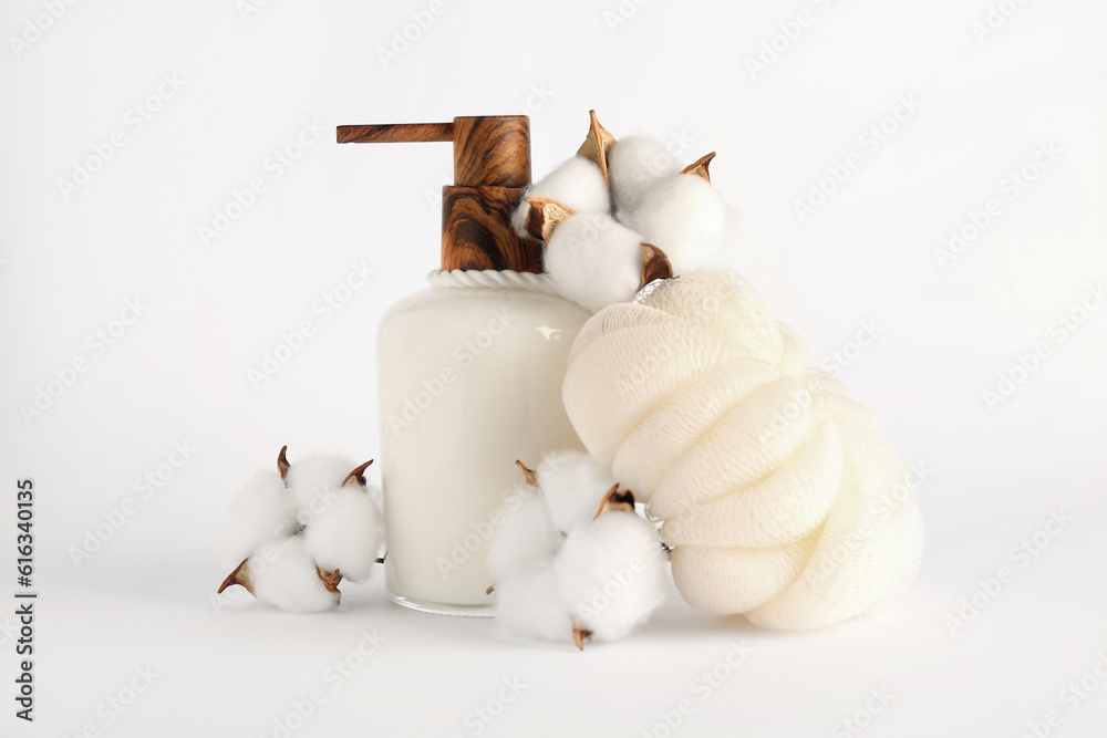 Bottle of cosmetic product, bath sponge and cotton flowers on light background