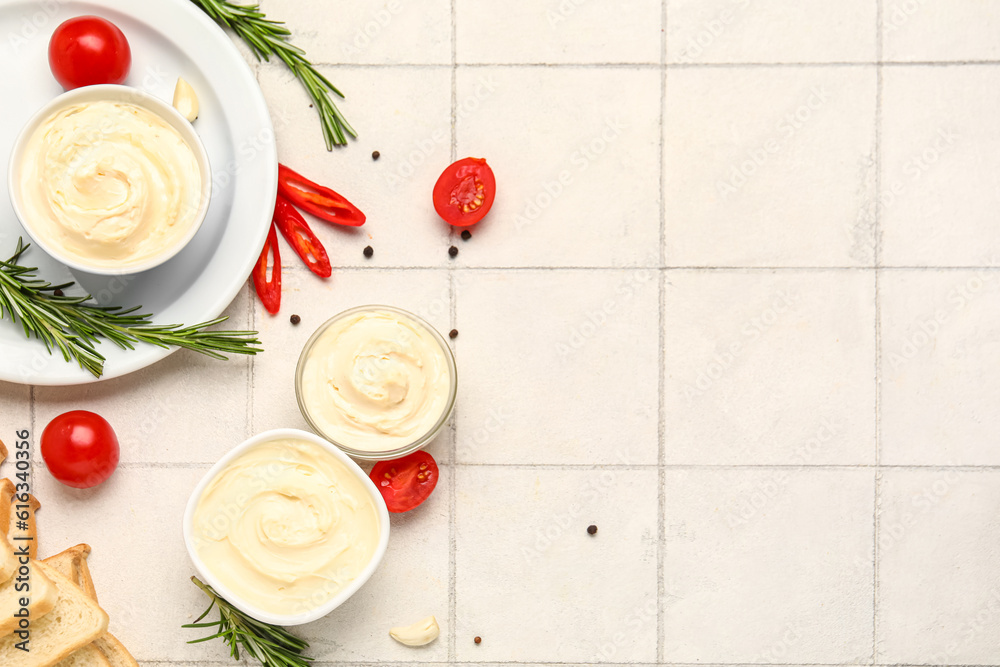 Bowls of tasty cream cheese on white tile background