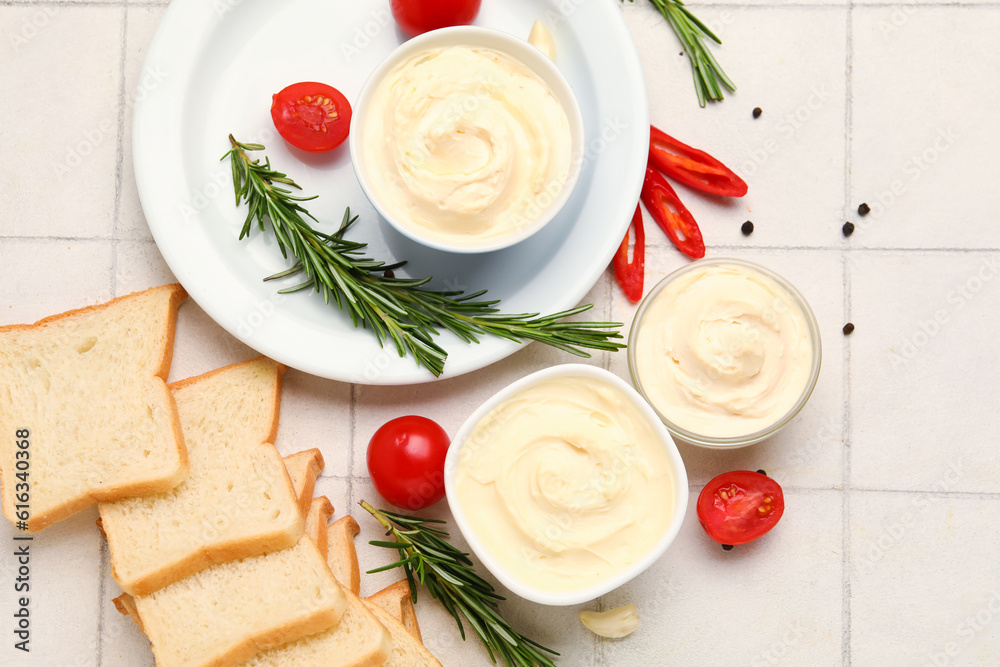 Bowls of tasty cream cheese and fresh bread on white tile background