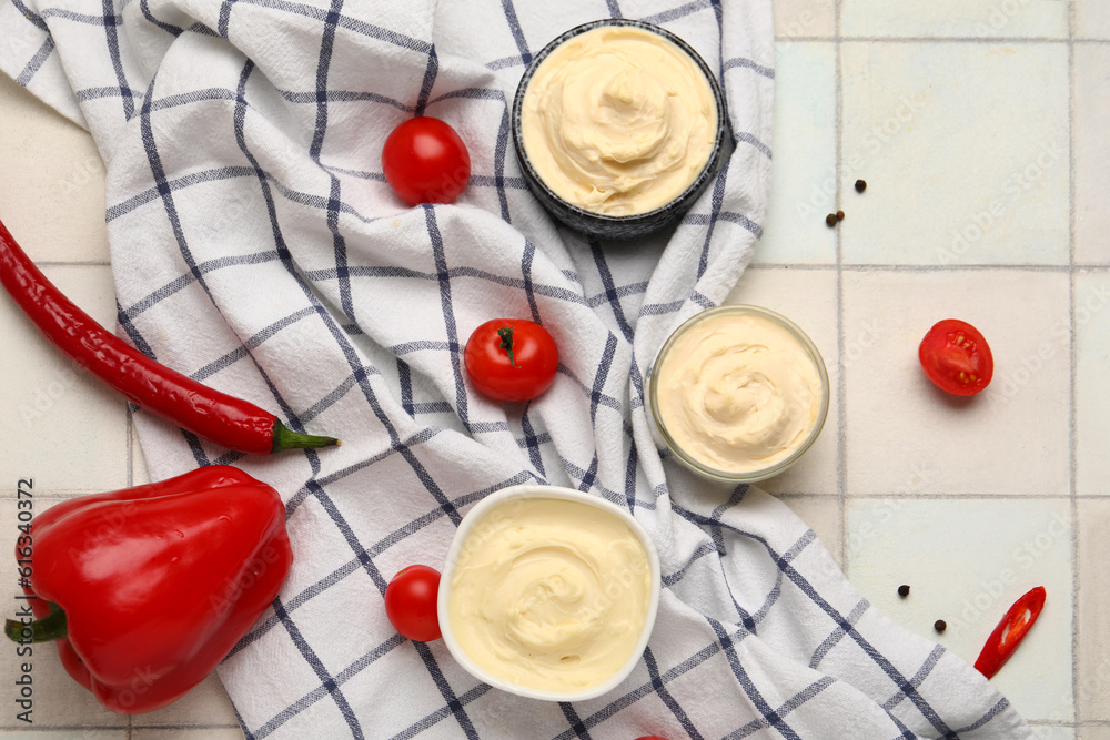 Bowls of tasty cream cheese on white tile background