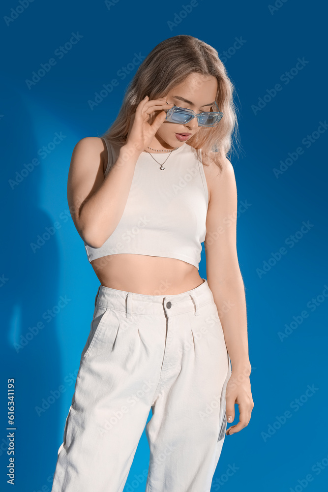 Young woman in stylish sunglasses on blue background