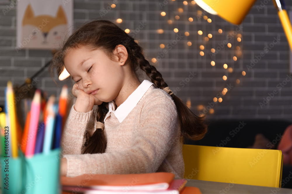 Sleepy little girl doing lessons at home late in evening