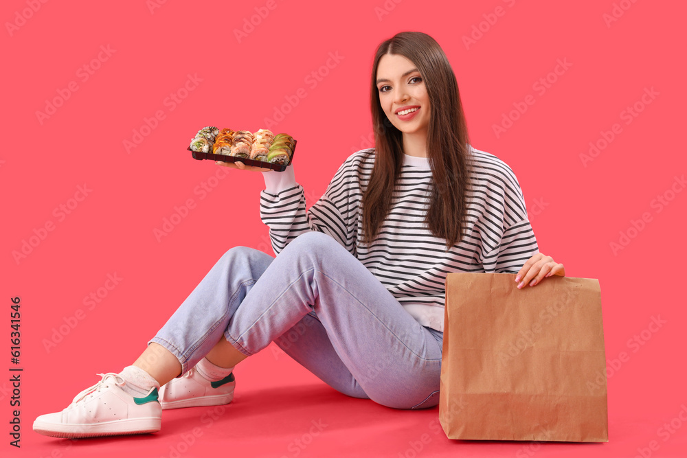 Young woman with sushi and paper bag sitting on red background