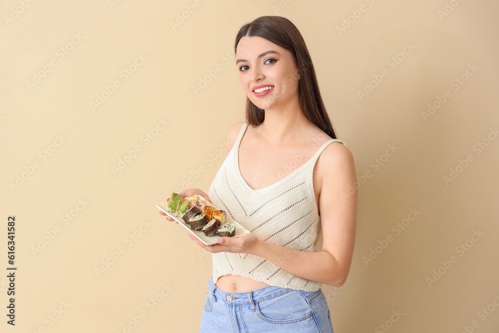 Young woman with sushi on beige background