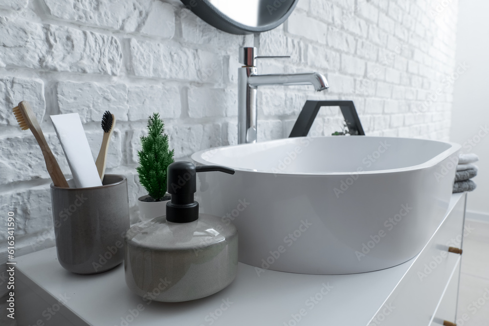 Sink bowl and bath accessories on table in bathroom, closeup