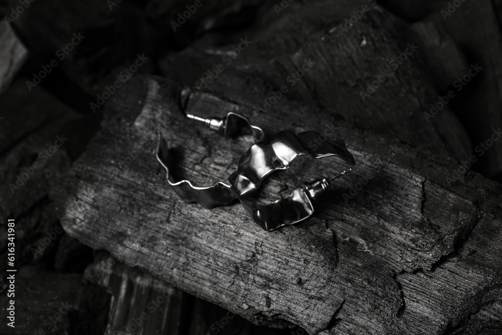 Beautiful earrings on black charcoal, closeup