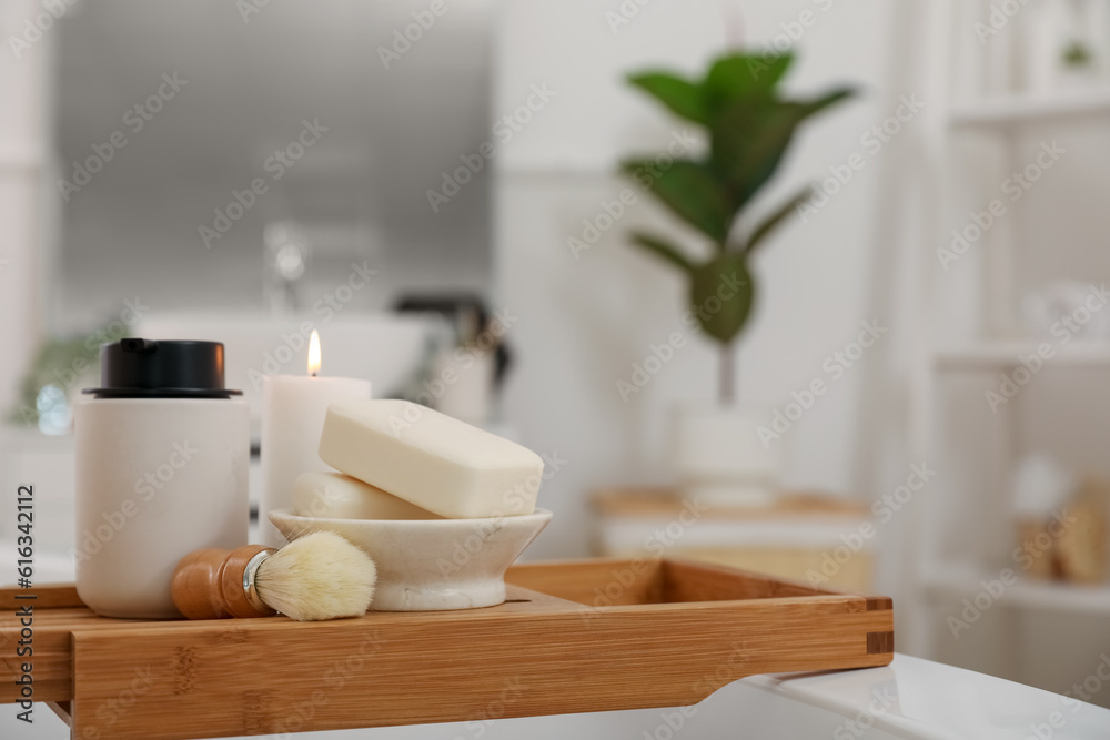 Shaving brush, soap bars and bath accessories on board in interior of bathroom, closeup