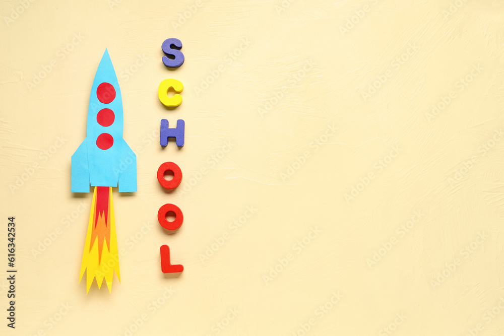 Paper rocket with word SCHOOL on beige background