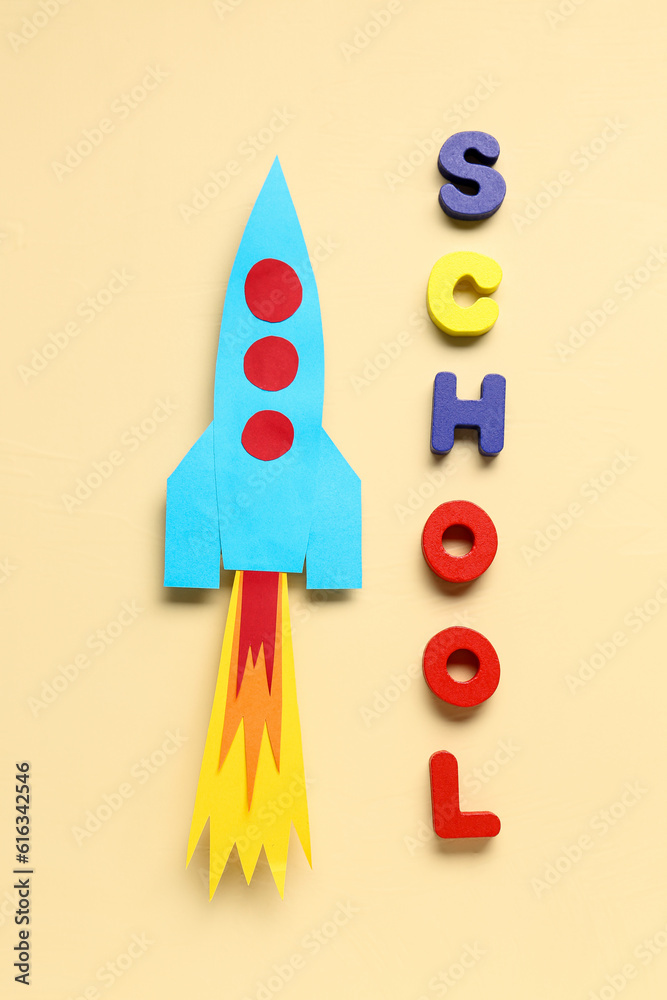 Paper rocket with word SCHOOL on beige background