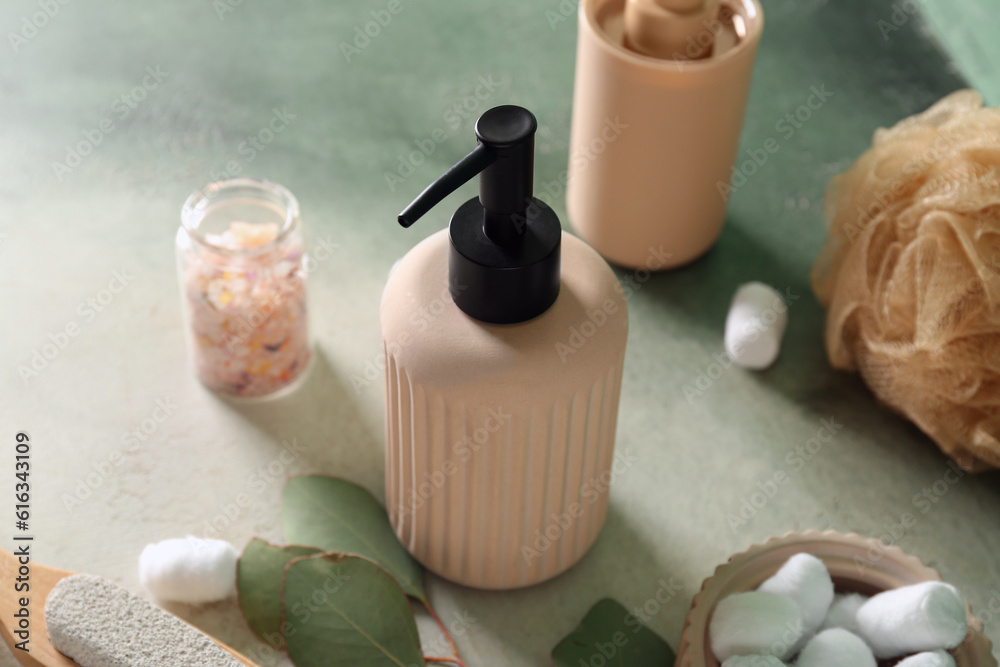 Bottle of cosmetic product, sea salt, sponge and cotton balls on color background, closeup