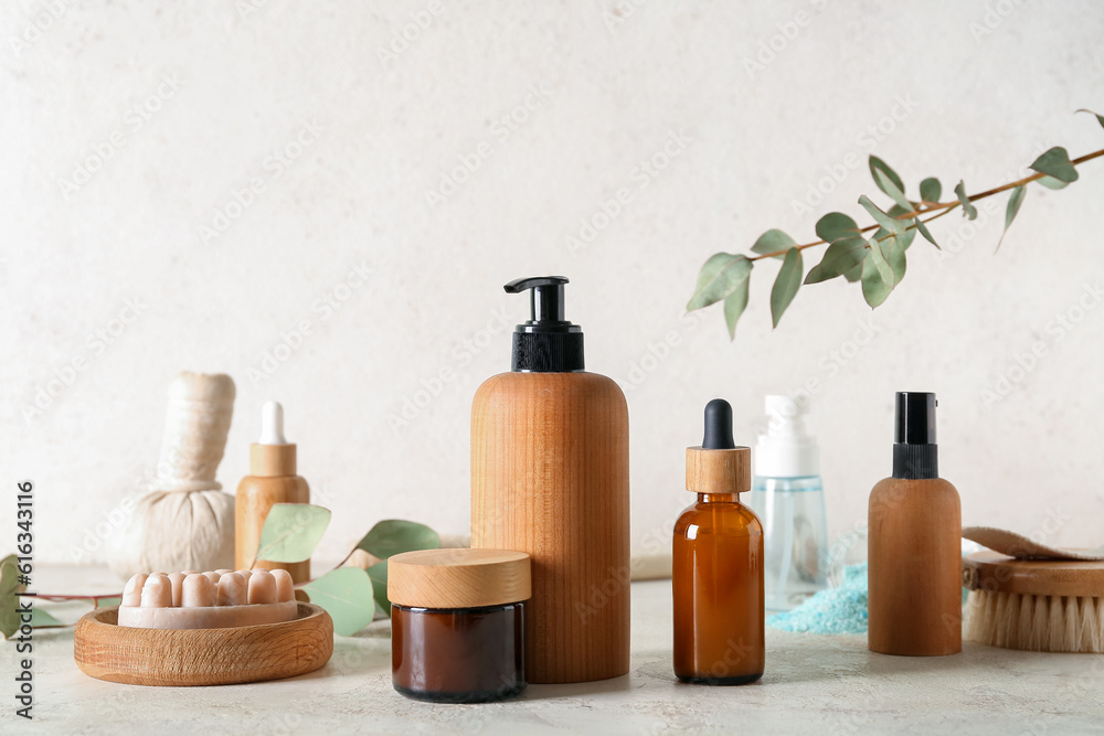 Bottles of cosmetic products, massage soap, herbal bag and cream on light background