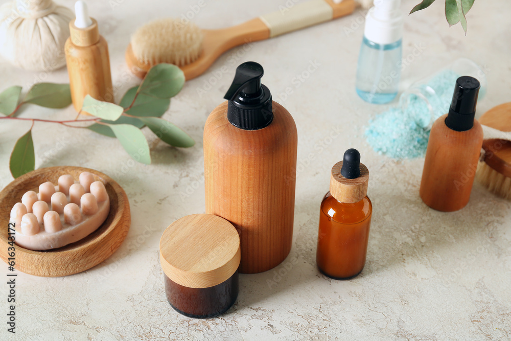 Bottles of cosmetic products, massage soap and cream on light background