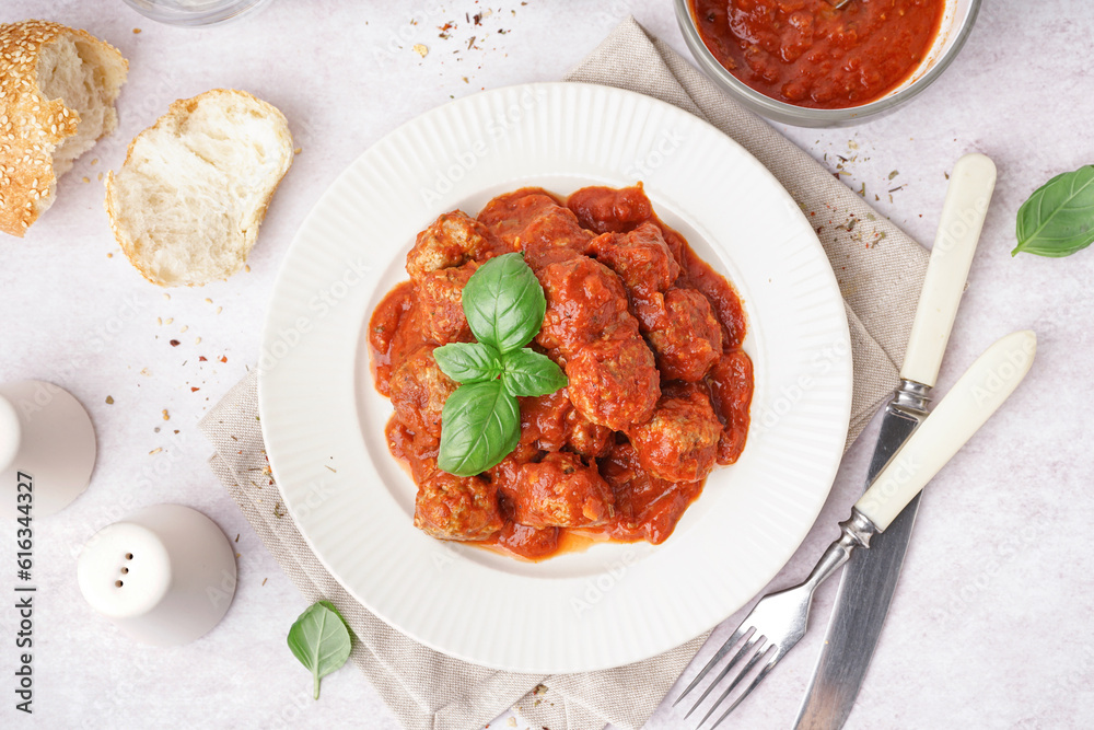 Plate of tasty meat balls with sauce on light background