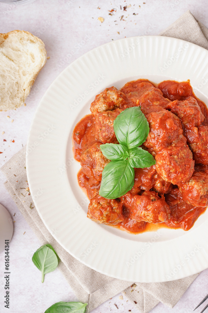 Plate of tasty meat balls with sauce on light background