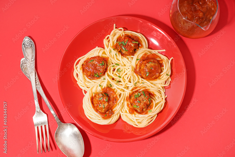 Plate of boiled pasta with tomato sauce and meat balls on red background