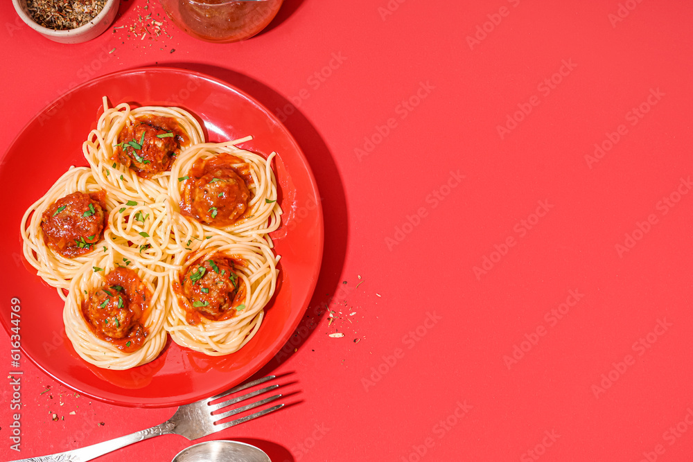 Plate of boiled pasta with tomato sauce and meat balls on red background