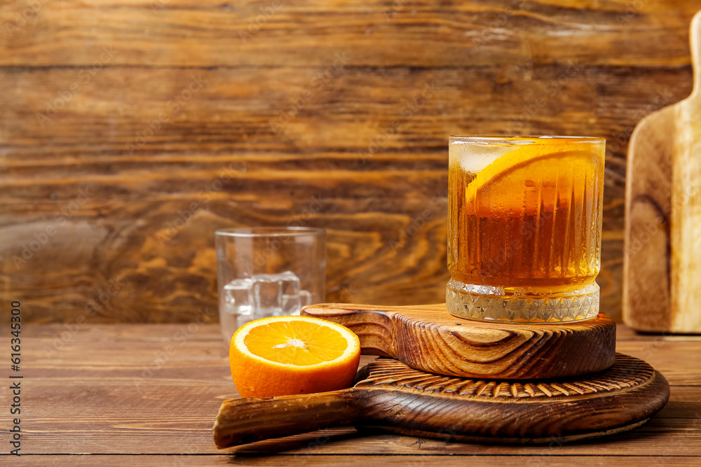 Boards with glass of ice tea and orange on wooden background