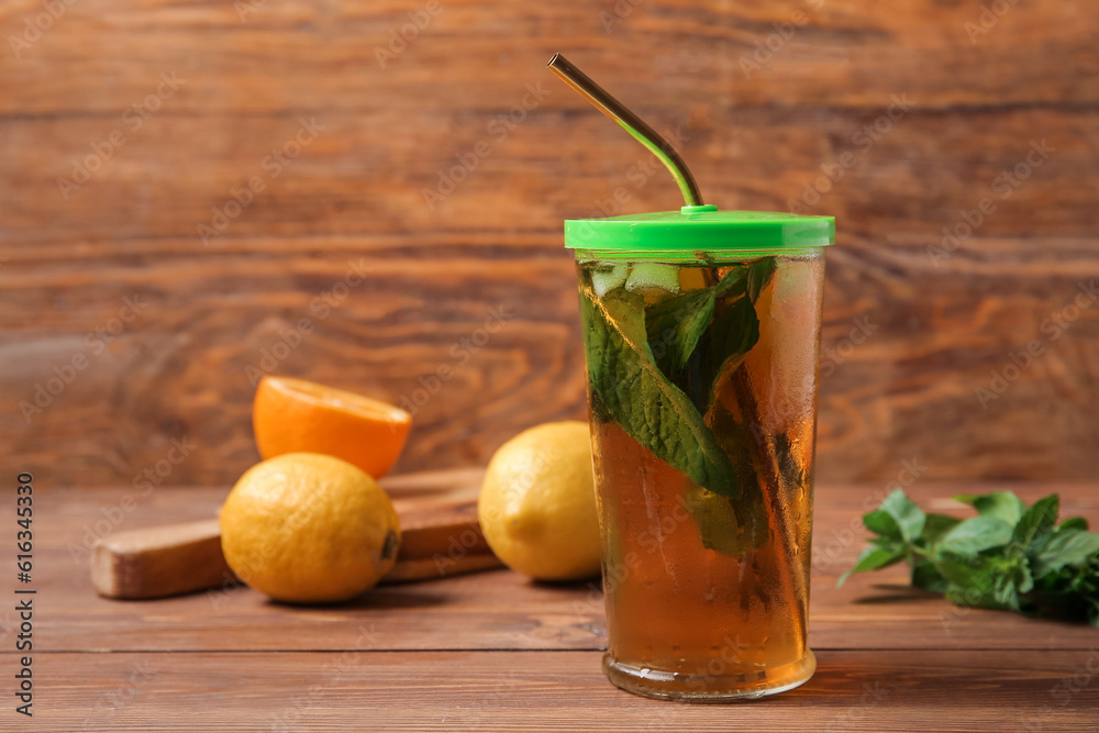 Glass of ice tea with mint and lemon on wooden background