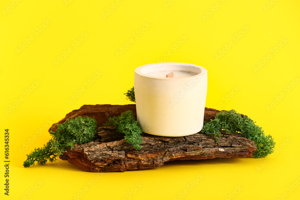 Holder with candle and tree bark on yellow background