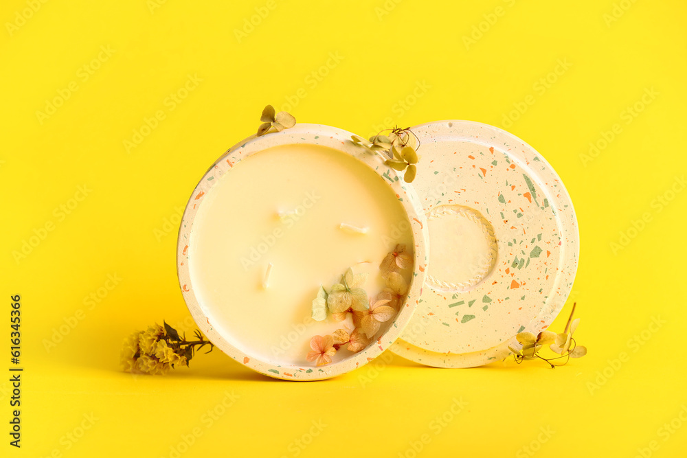 Holder with candle and flowers on yellow background