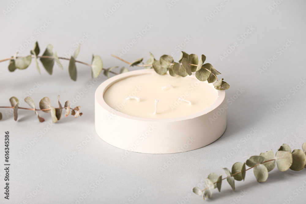 Holder with candle and eucalyptus on grey background