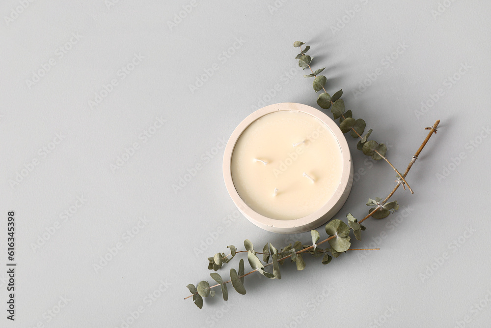 Holder with candle and eucalyptus on grey background