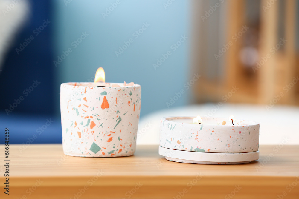 Holders with burning candles on table in room, closeup