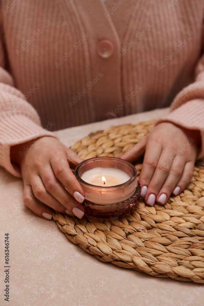 Woman with burning candle on table