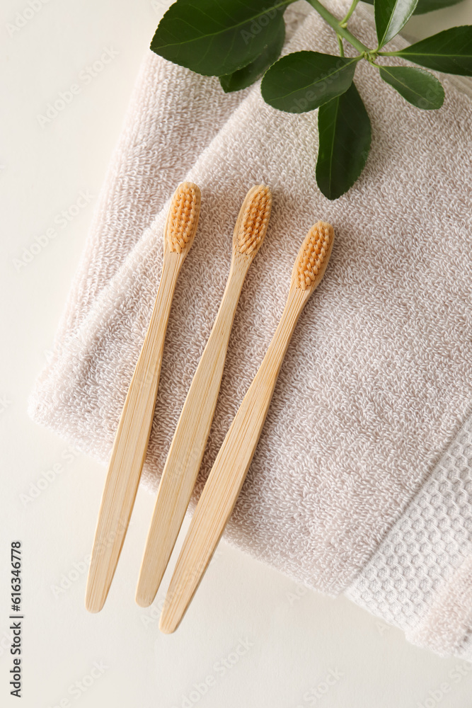 Bamboo tooth brushes and towel on light background, top view