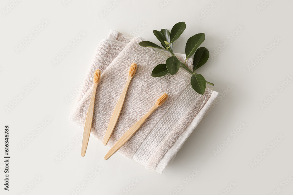 Bamboo tooth brushes and towel on light background, top view