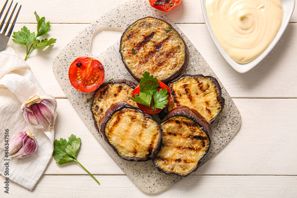 Delicious grilled eggplants, sauce and tomatoes on white wooden background