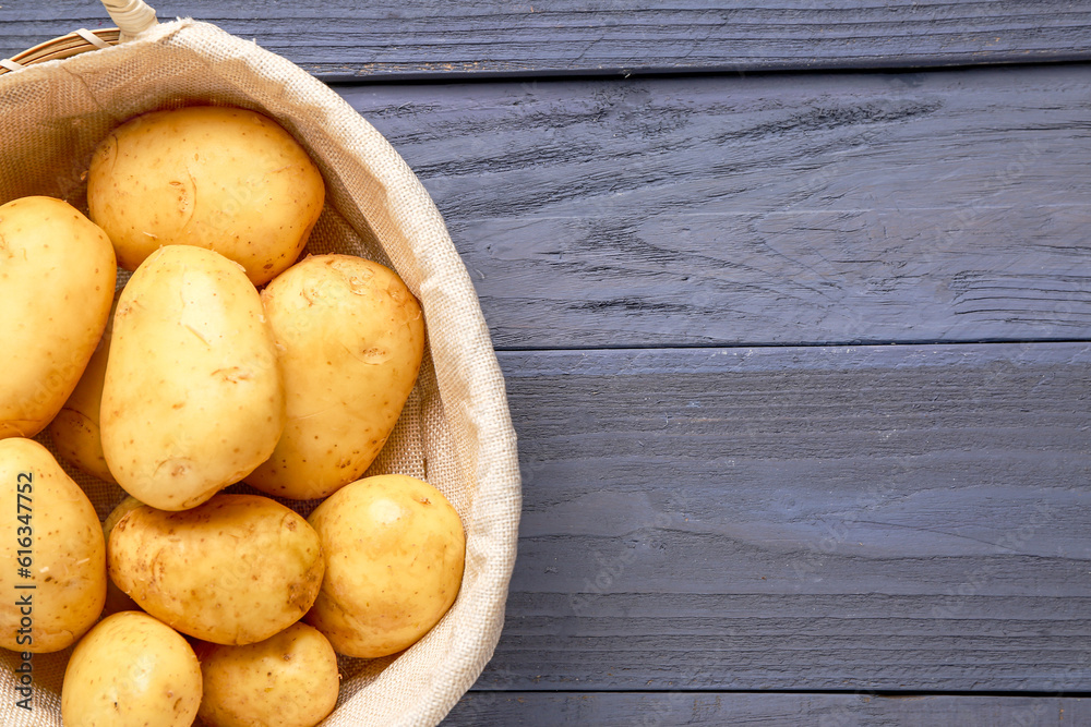 Wicker basket with raw baby potatoes on blue wooden background