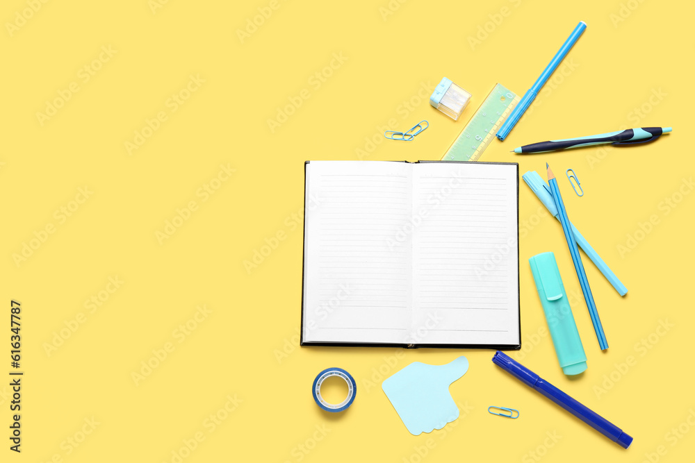 Notebook with different school stationery on yellow background