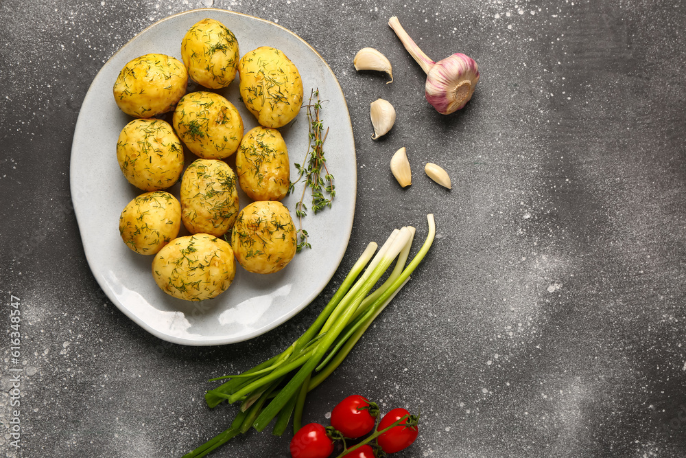 Plate of boiled baby potatoes with dill and garlic on grey background