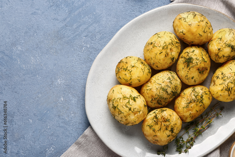 Plate of boiled baby potatoes with dill on blue background