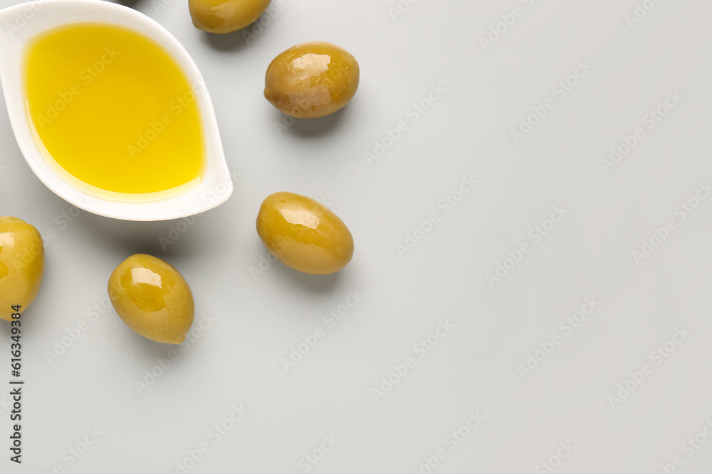 Bowl with fresh olive oil on grey background