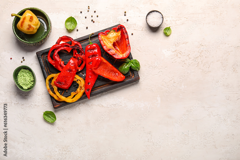 Wooden board with tasty grilled peppers on light background