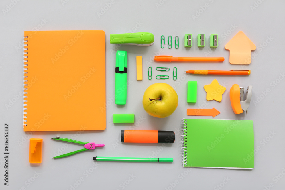 Fresh apple with different stationery on grey background