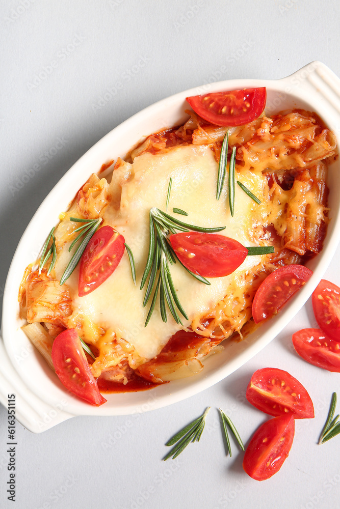 Baking dish of pasta with tomato sauce and cheese on white background