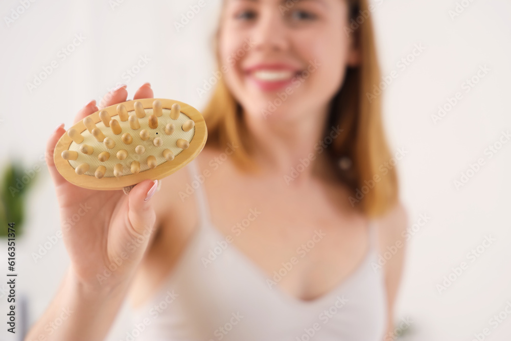 Young woman with anti-cellulite brush in bathroom, closeup