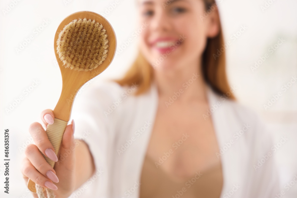 Young woman with anti-cellulite brush in bathroom, closeup