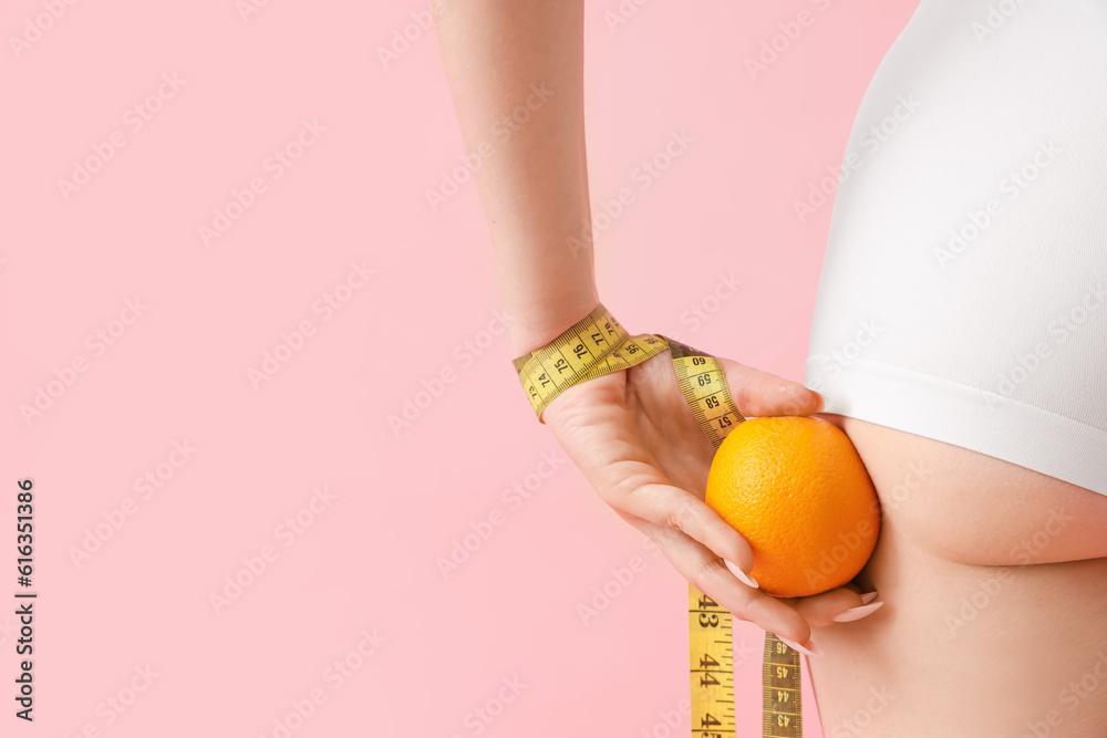 Young woman with measuring tape and orange on pink background, back view