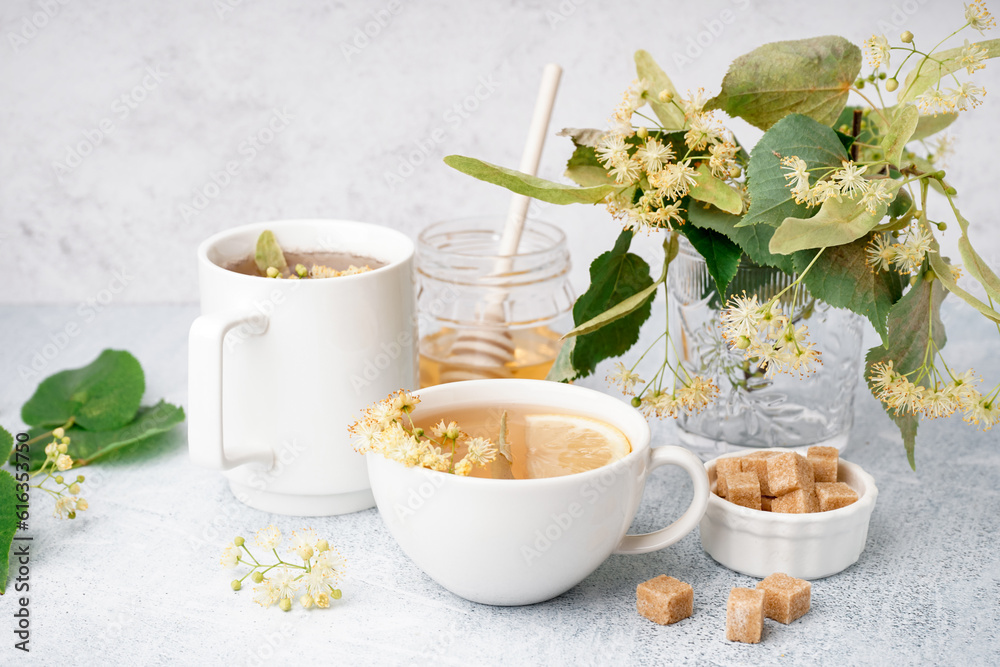 Cups of linden tea and jar with honey on white background