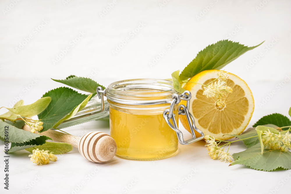 Jar with linden honey and lemon on white background