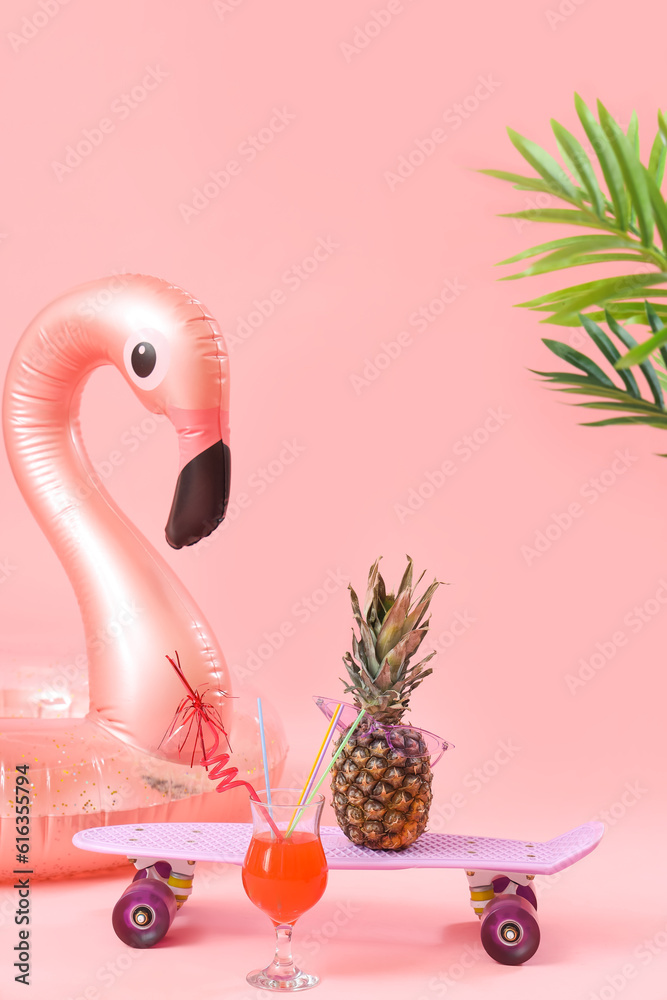 Inflatable ring with cocktail, skateboard and pineapple on pink background. Travel concept