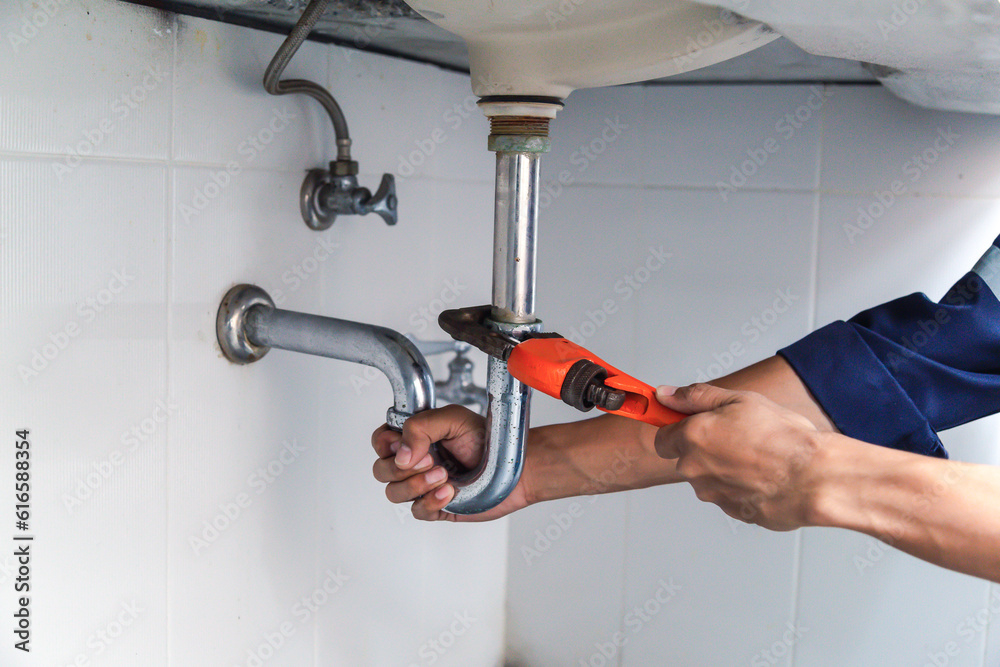 Plumber working in the bathroom, plumbing repair service, repairing leaking sinks with adjustable wr