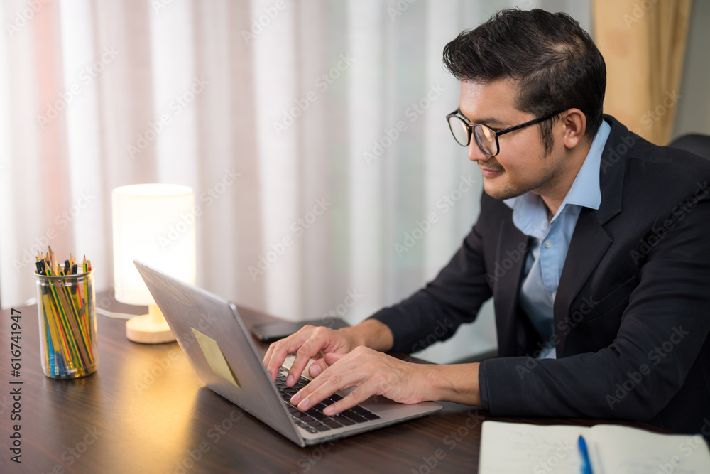 A businessman sitting at home working with laptop on desk.