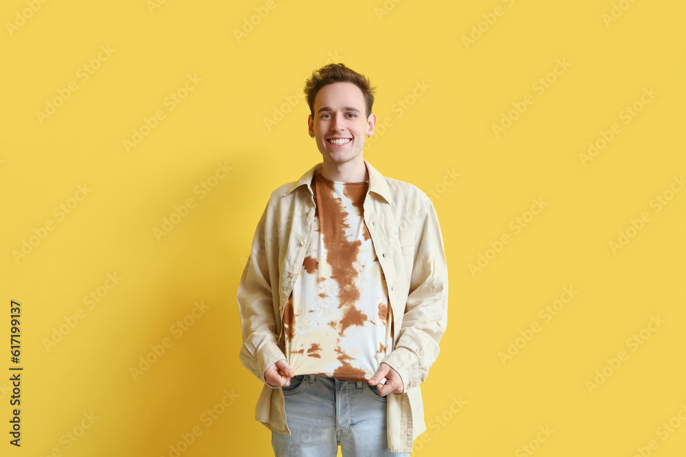 Young man in tie-dye t-shirt on yellow background